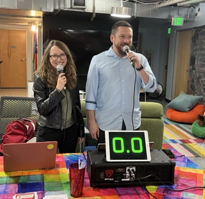 Two people stand holding microphones.